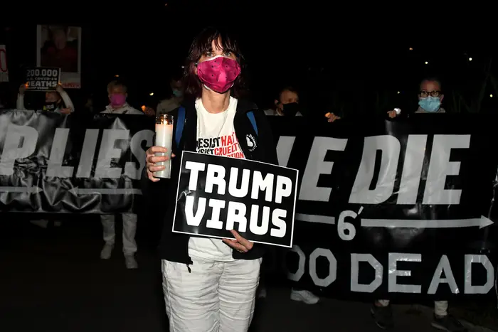 A photo of someone holding a sign reading "Trump Virus" at March for the Dead Fight for the Living, Central Park
